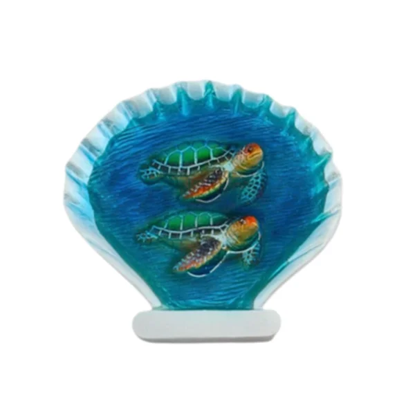 Scallop-shell-shaped resin frame magnet with two sea turtles swimming in blue water, on a white stand